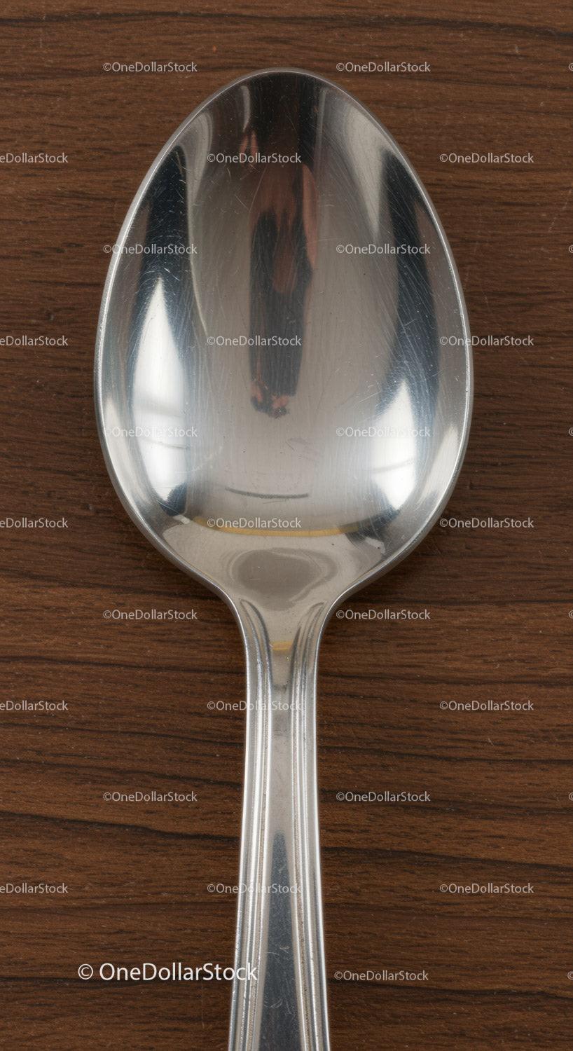Close up of stainless steel spoon on wooden surface