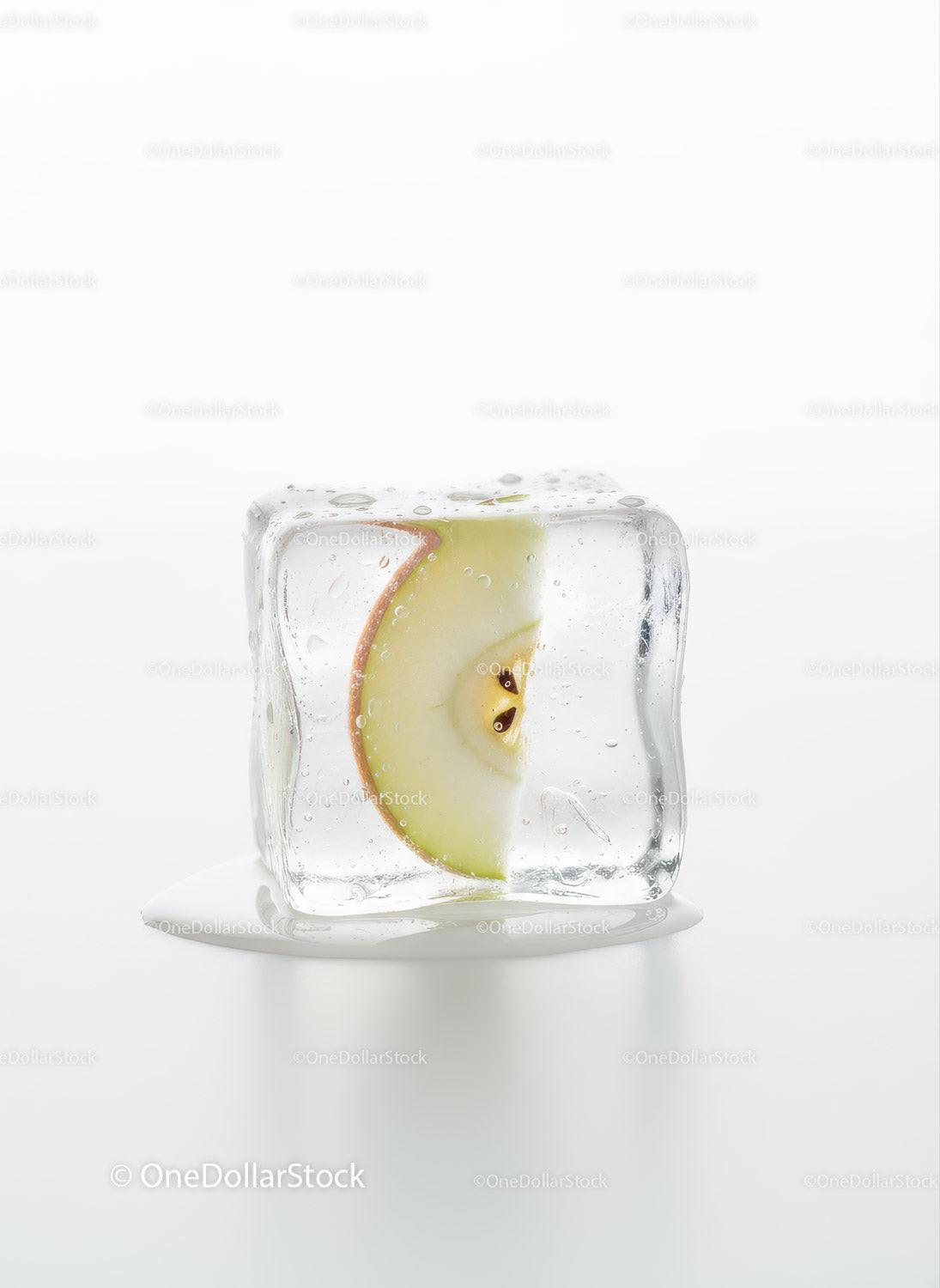 Green apple slice frozen inside melting ice cube