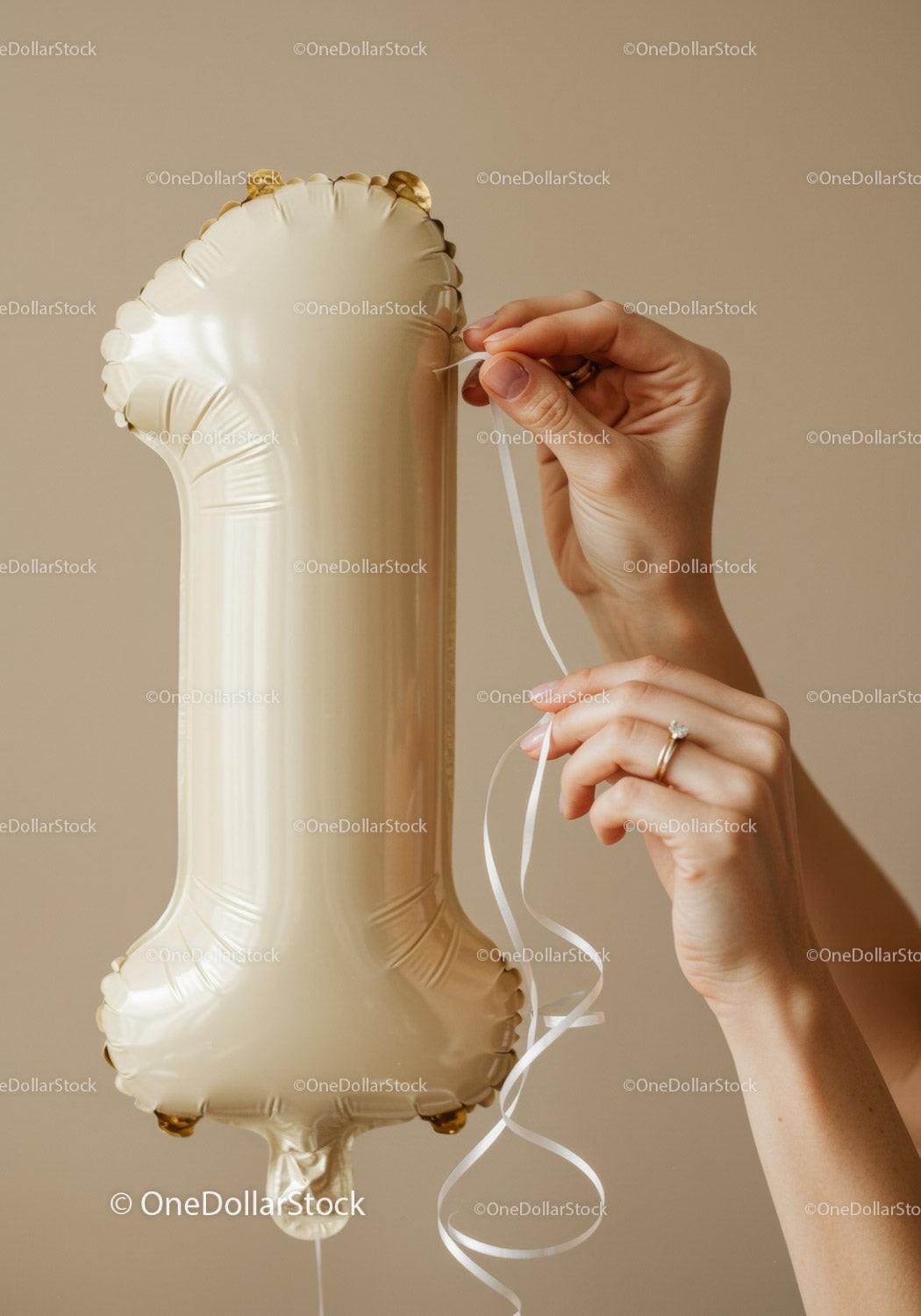 Hands tying ribbon on number one shaped balloon