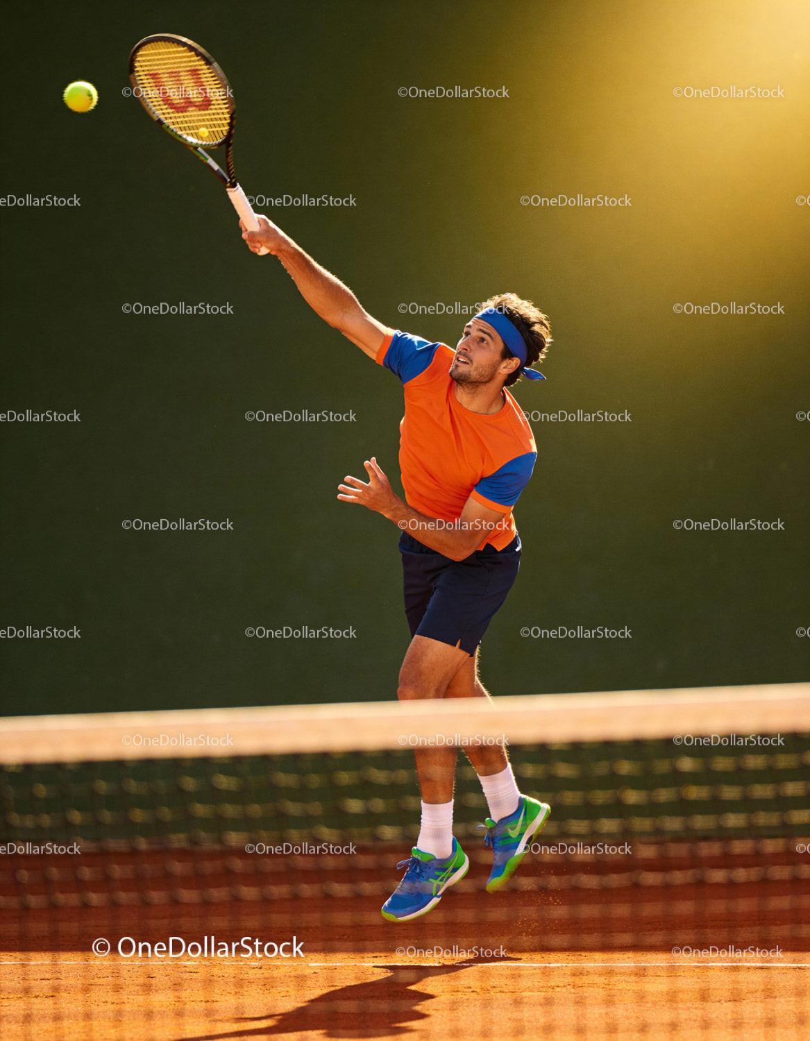 Male tennis player performing a jump serve on clay court