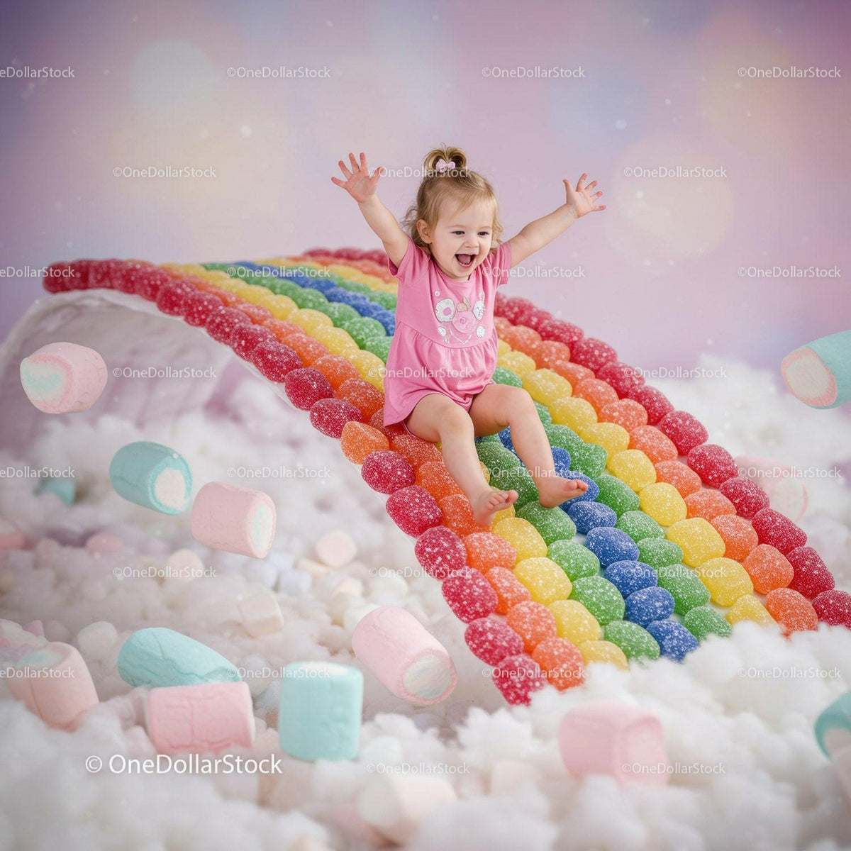 Joyful toddler sliding down colorful candy rainbow