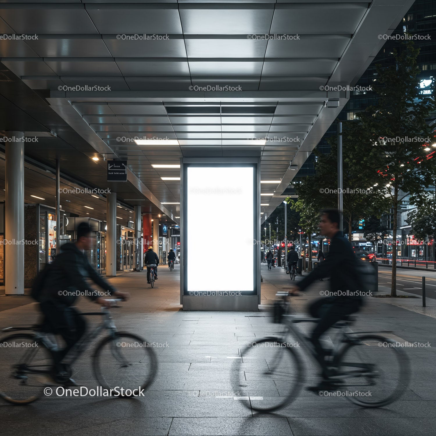 Urban commuters cycling past illuminated city billboard