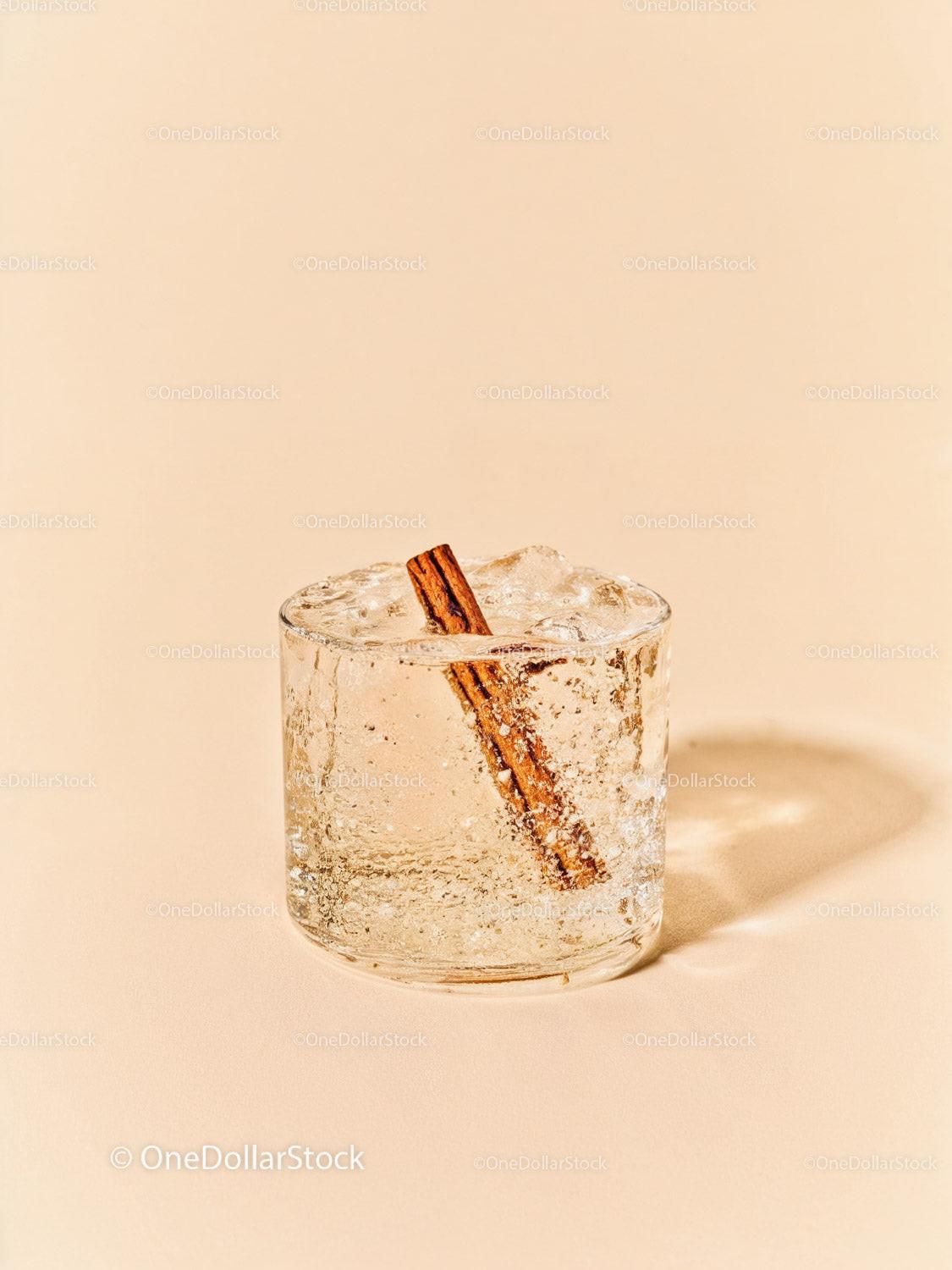 Refreshing iced drink with cinnamon stick on beige background