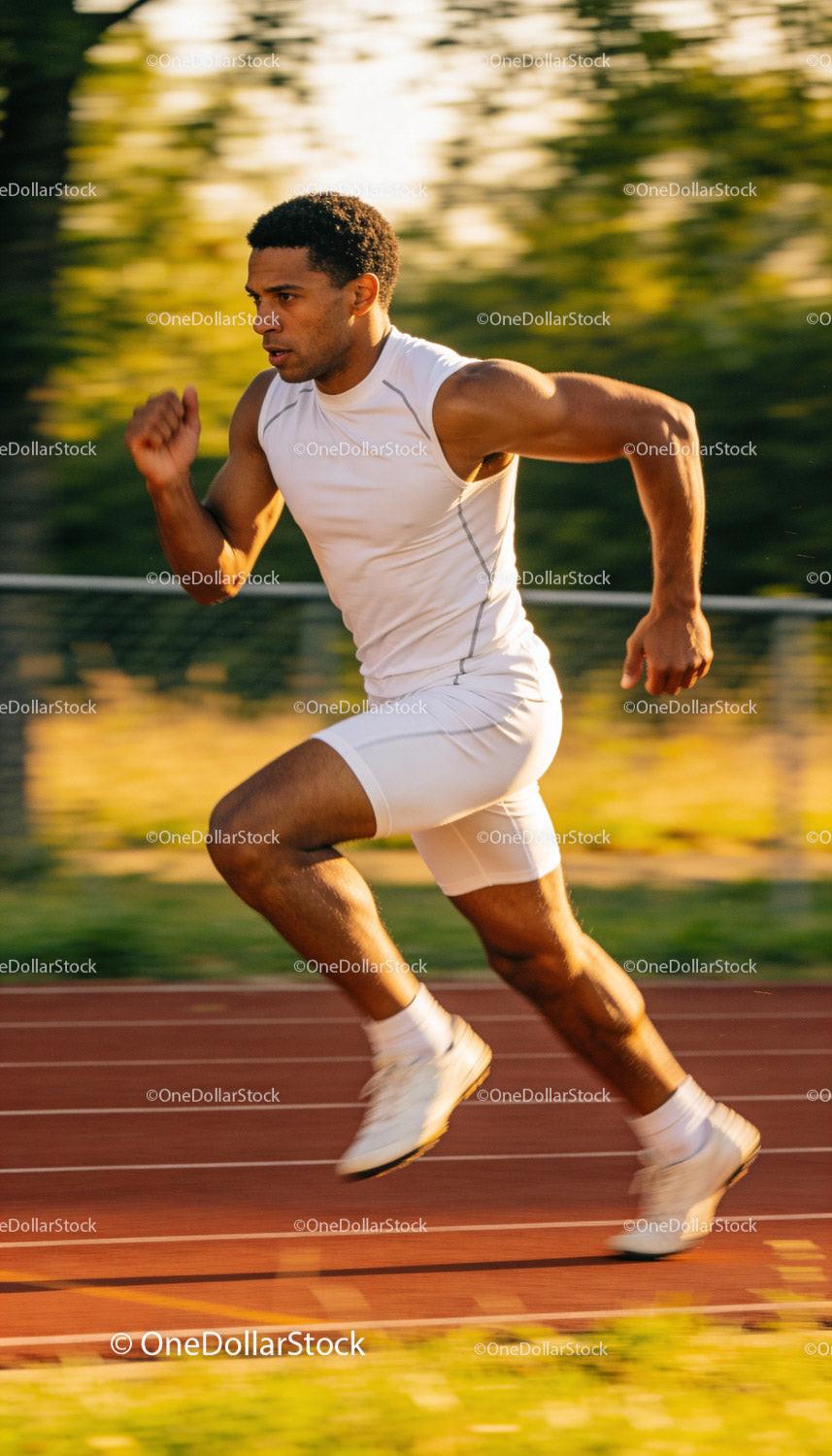 Focused male sprinter accelerating on the track outdoors