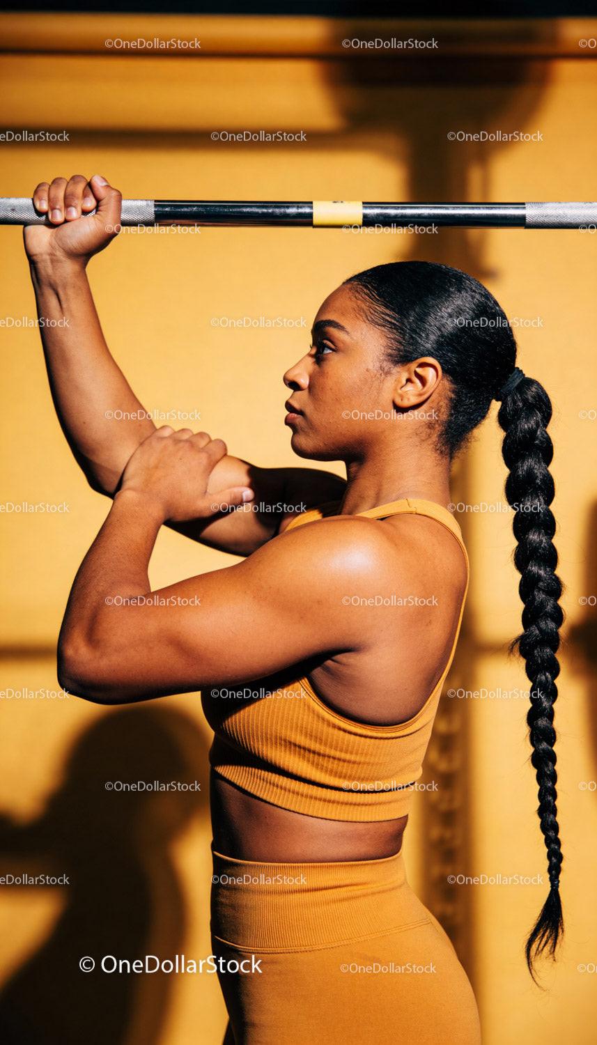 Focused woman lifting barbell in warm gym lighting