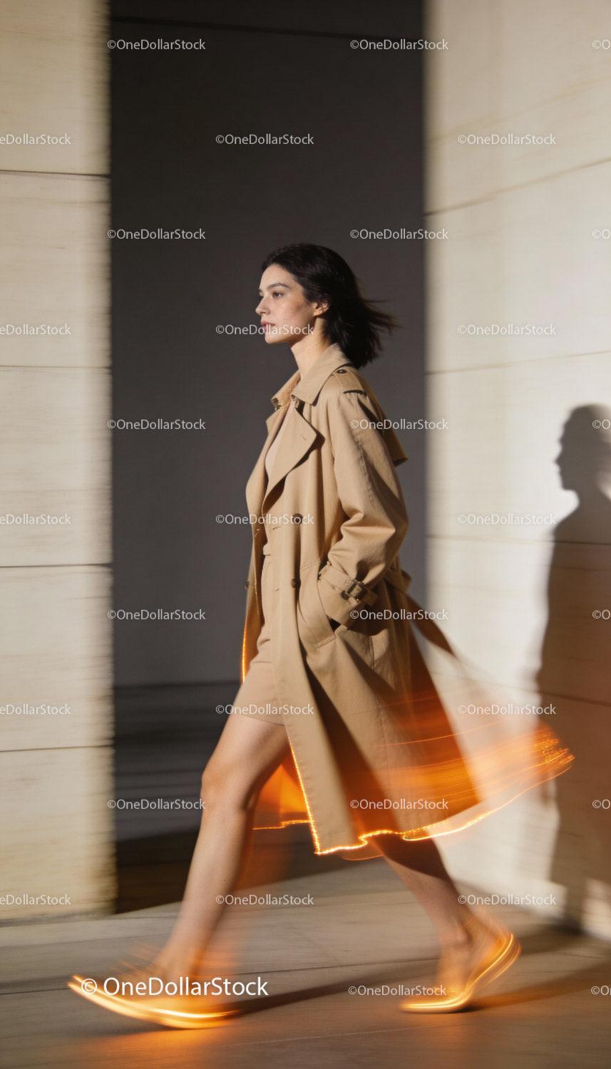 Stylish woman walking in beige trench coat and dress