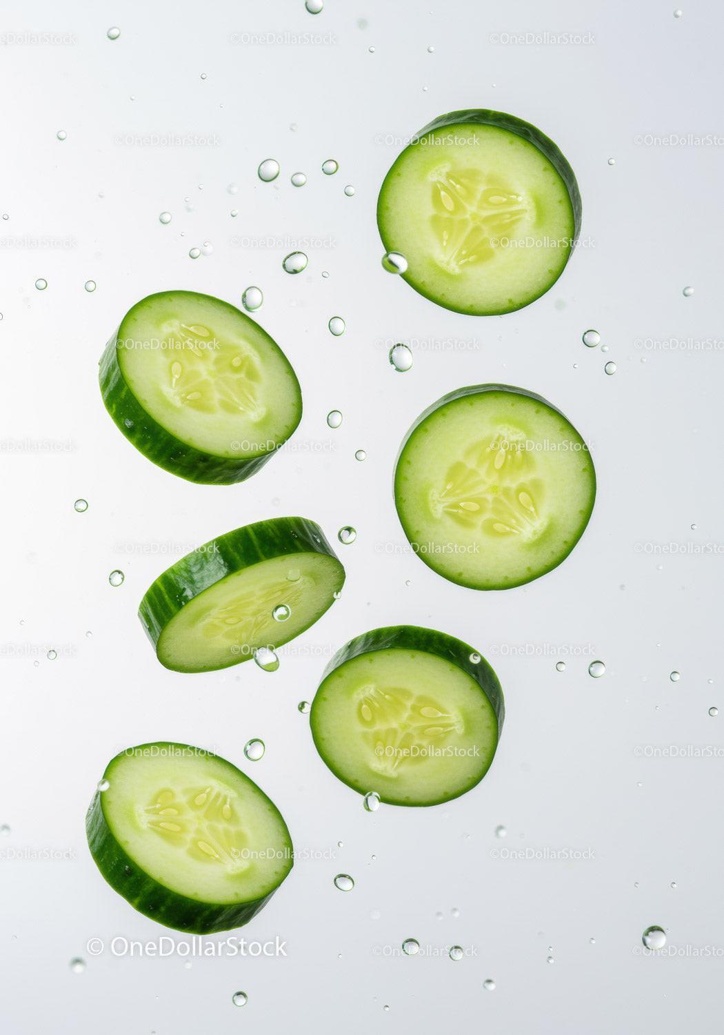 Fresh cucumber slices floating in clear water droplets
