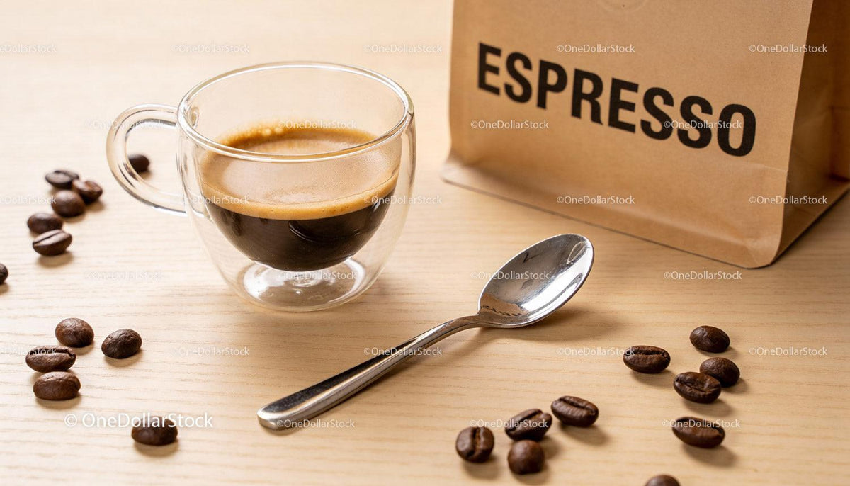 Freshly brewed espresso in clear glass cup with coffee beans