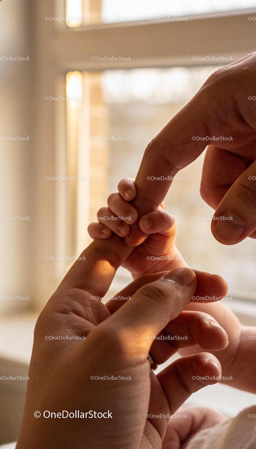 Tender moment of baby holding adult finger gently