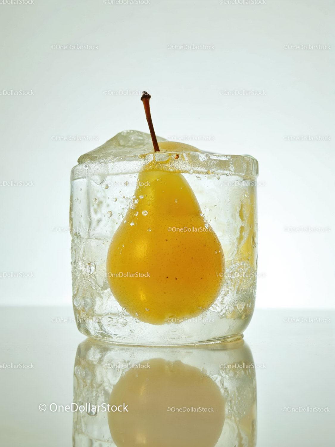 Yellow pear frozen inside a clear ice cube with reflection