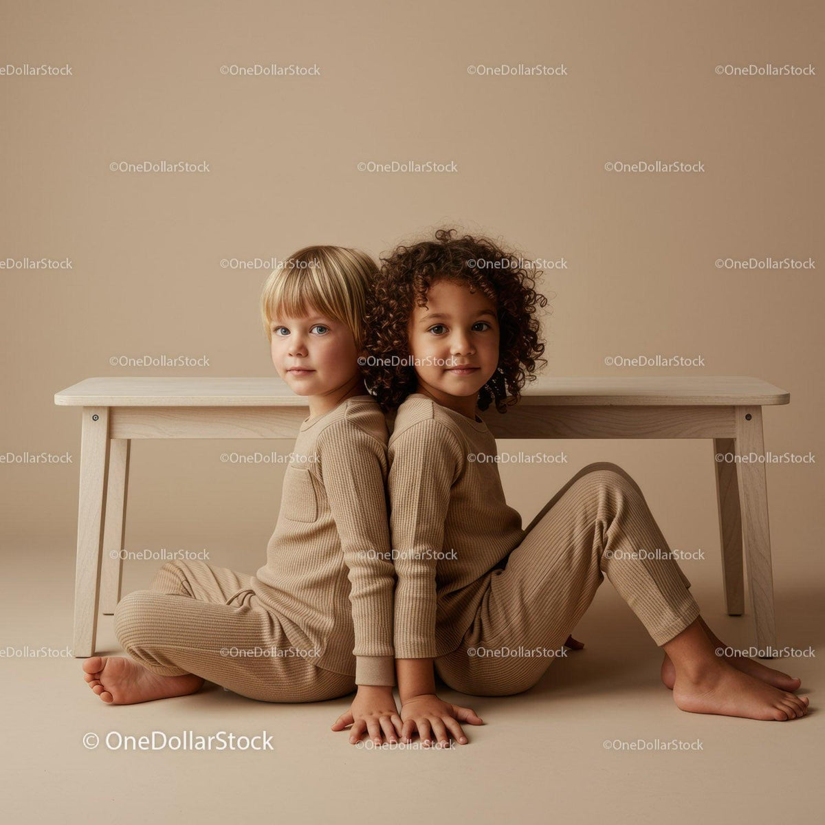 Two children sitting back to back near wooden bench
