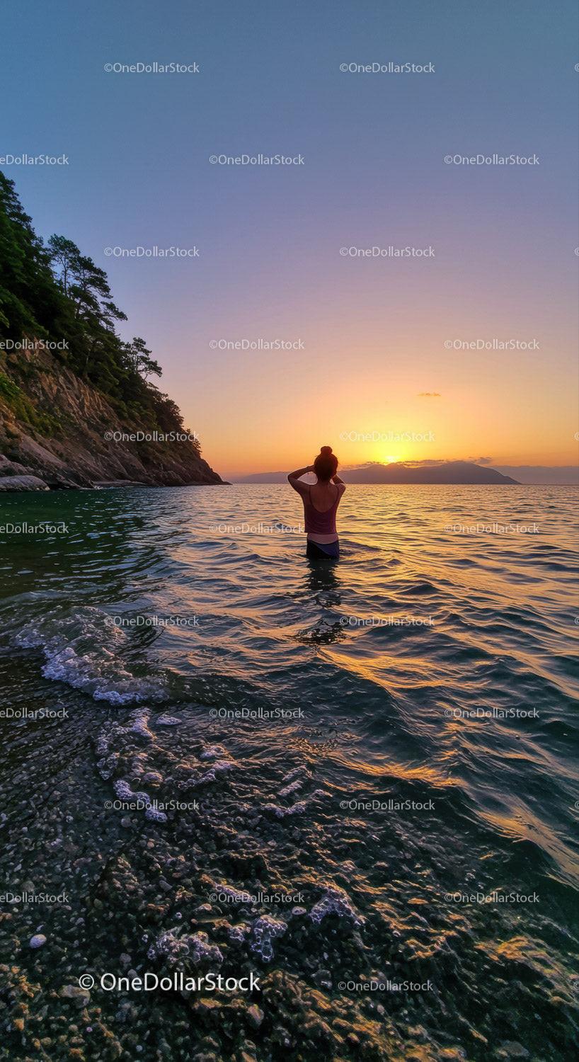 Serene Woman Swimming at Sunset Over Rocky Coastline in Nature