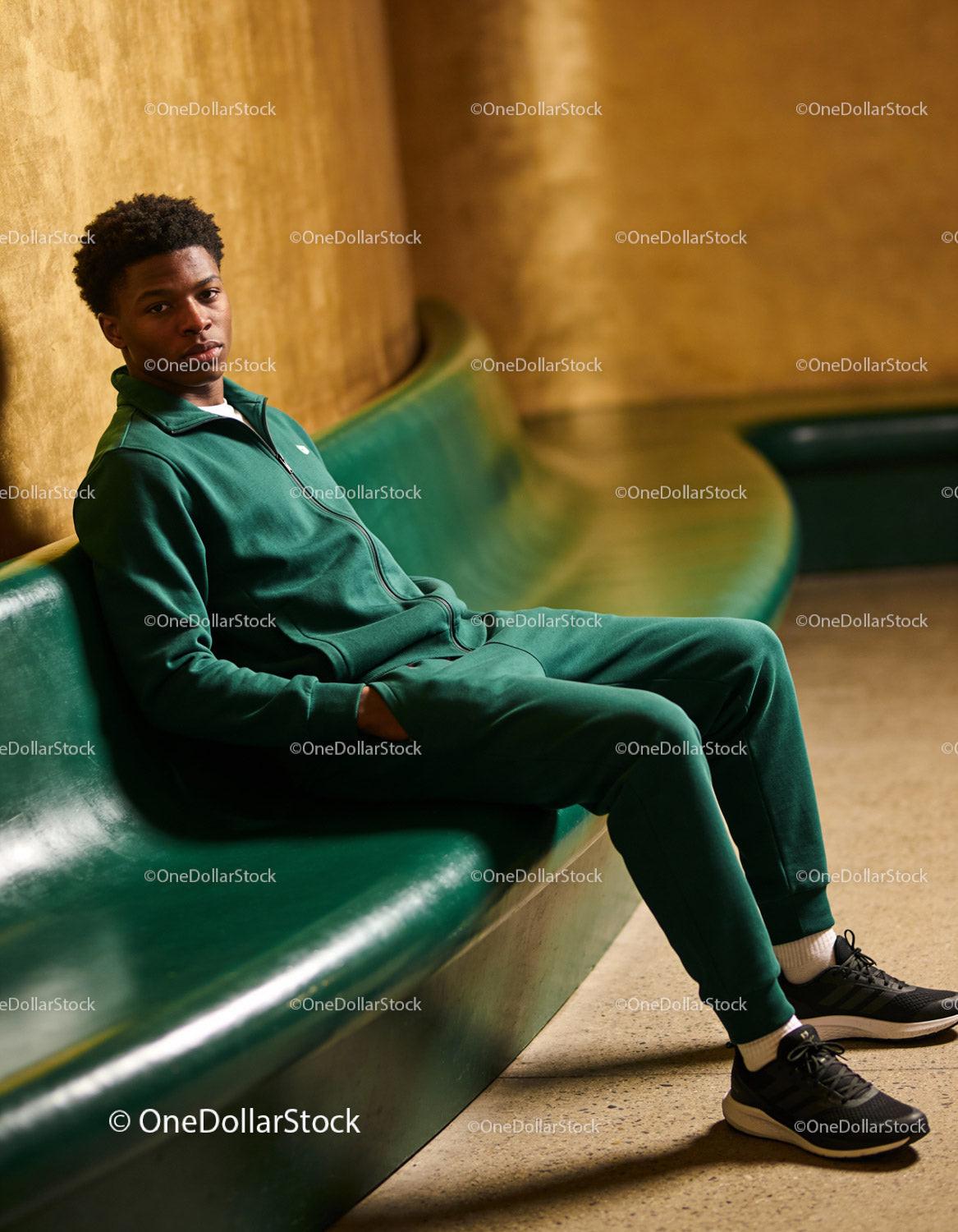 Young man relaxing on curved green bench indoors