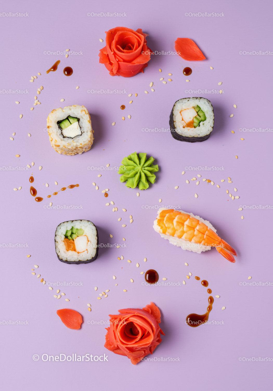 Assorted sushi rolls with garnishes on pastel background