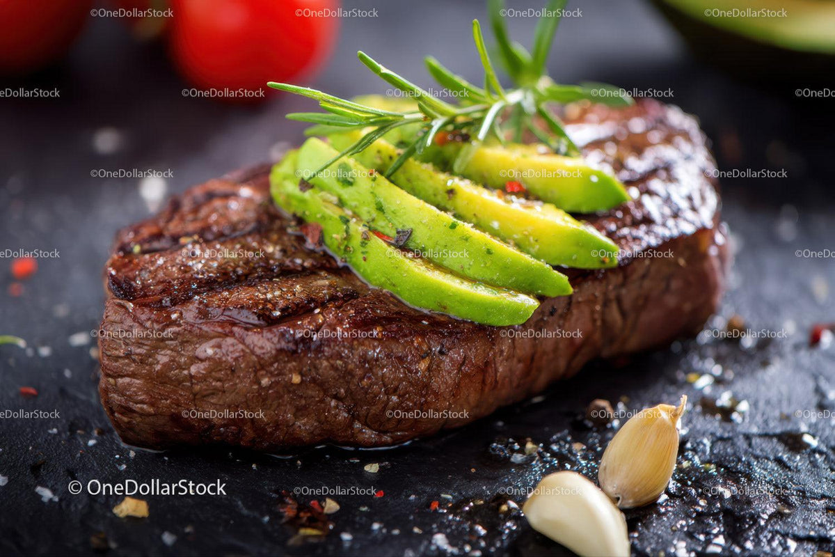 Juicy Grilled Steak with Slices of Avocado and Fresh Herbs