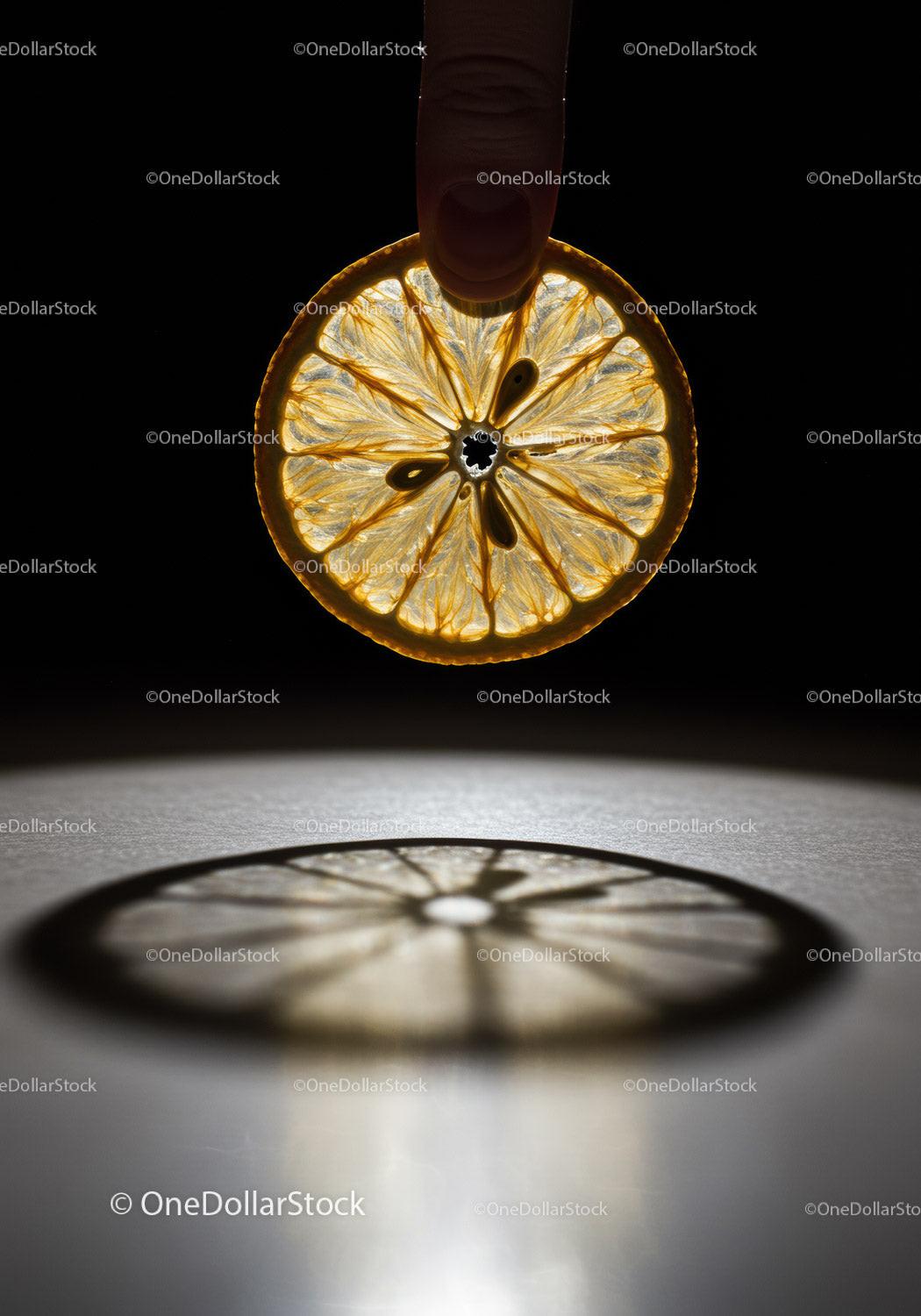 Finger Holding Thin Slice of Lemon with Shadow
