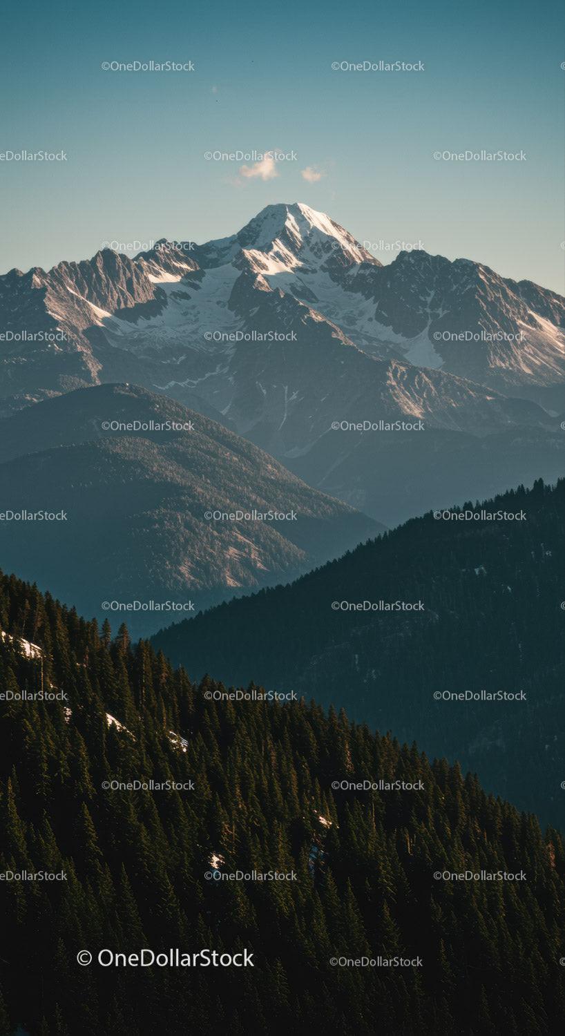 Majestic Snow-Covered Mountain Peak with Forested Hills