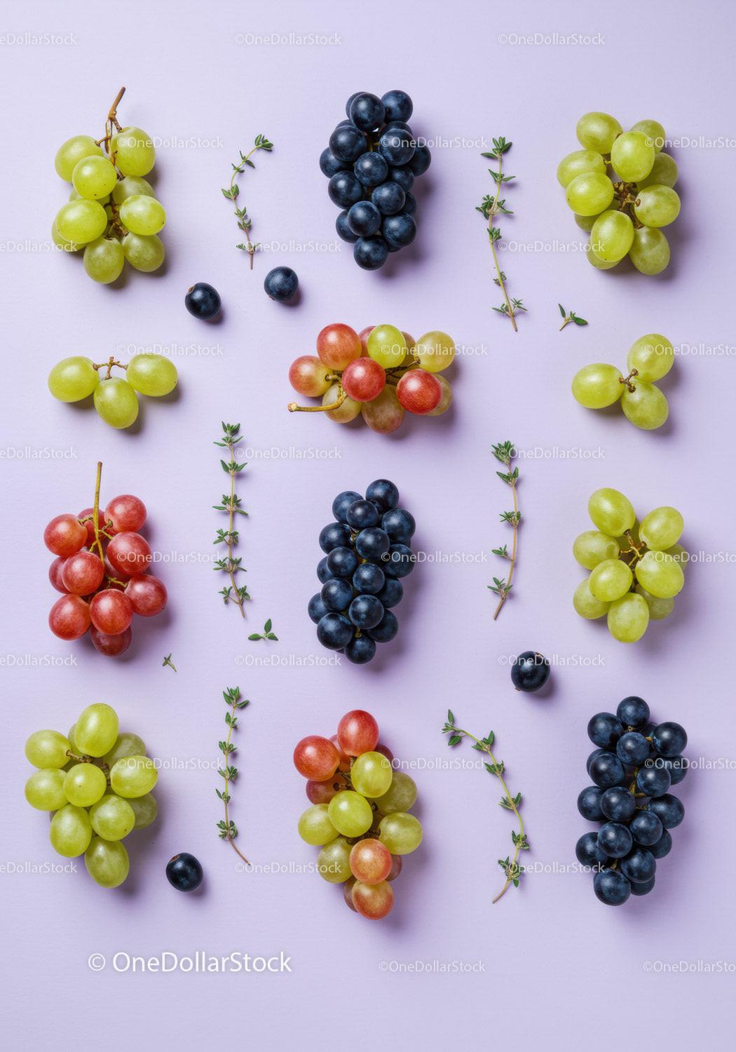 Variety of fresh grapes and thyme sprigs on pastel surface
