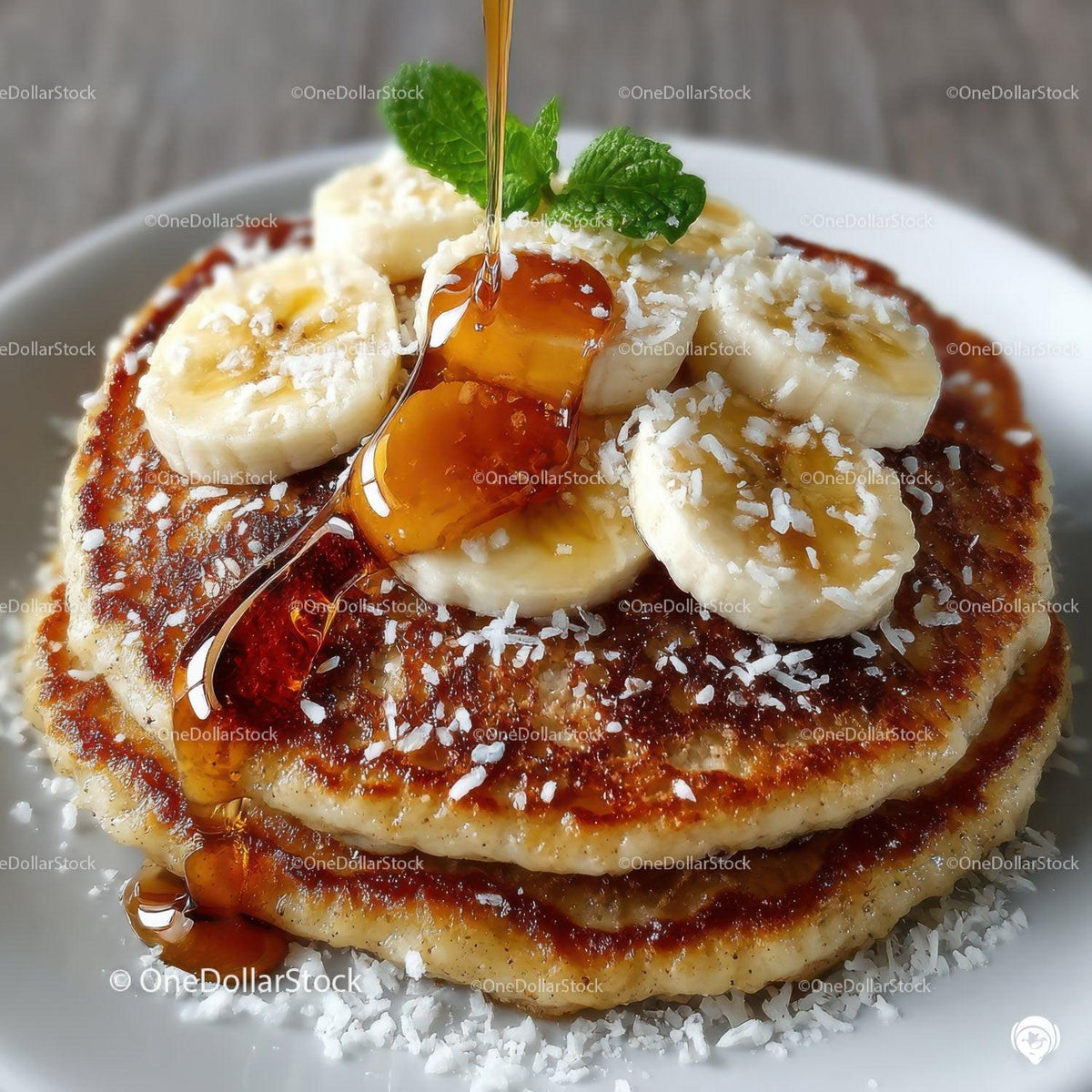 Banana Pancakes with Syrup and Fresh Mint on a White Plate
