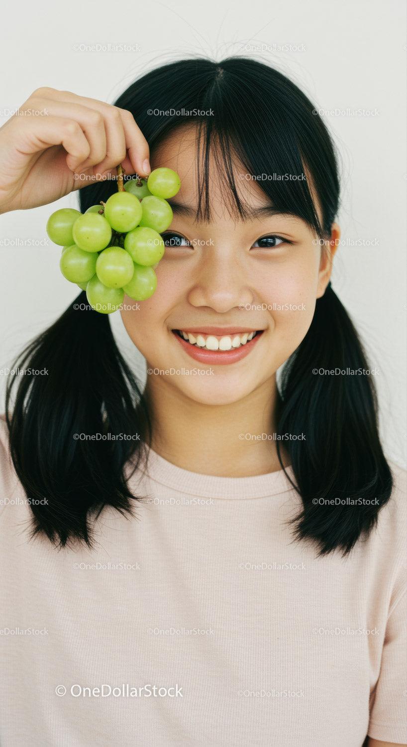 Smiling Girl Holding Green Grapes with Joy and Freshness