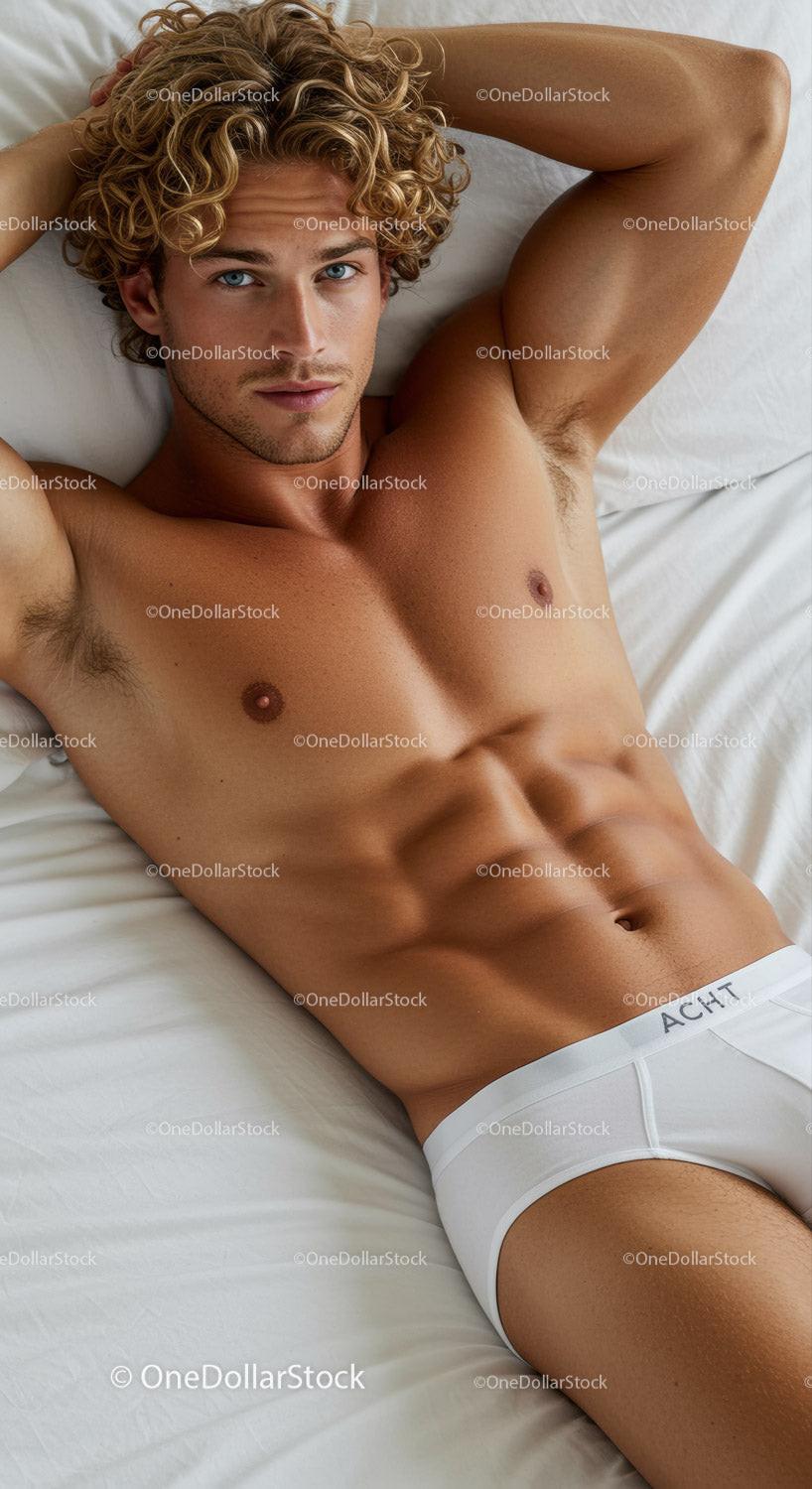 Athletic young man with curly hair reclining on bed