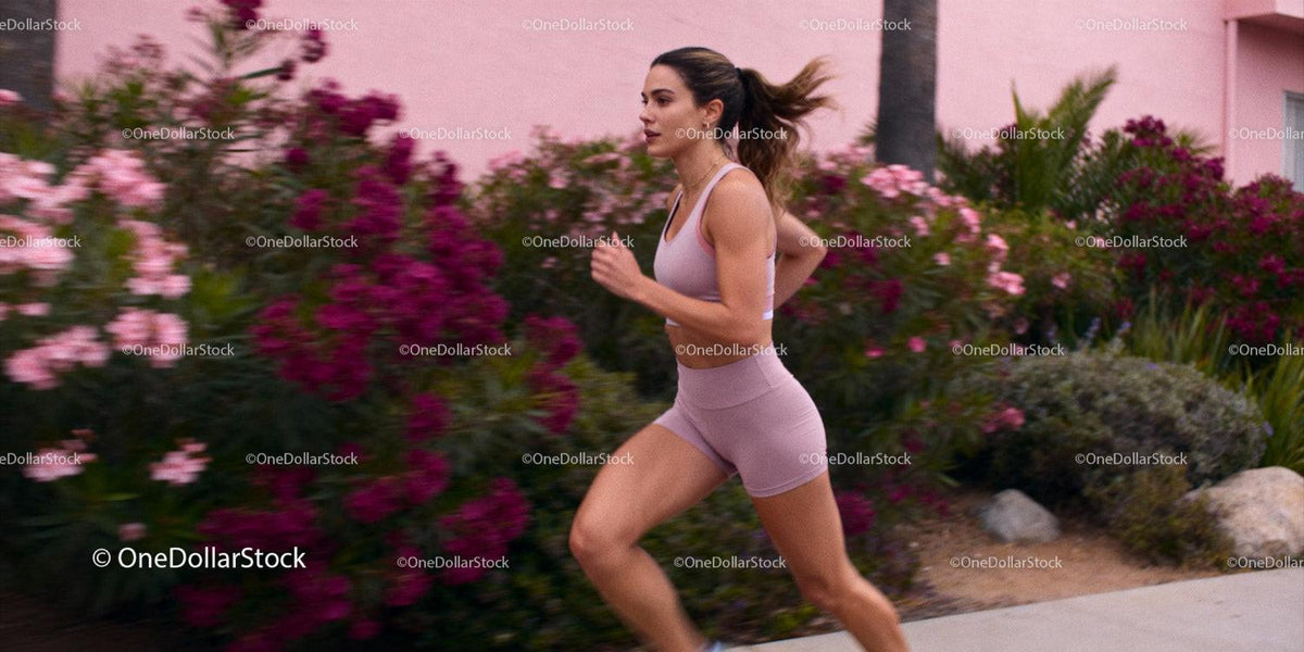 Focused young woman jogging past vibrant garden wall