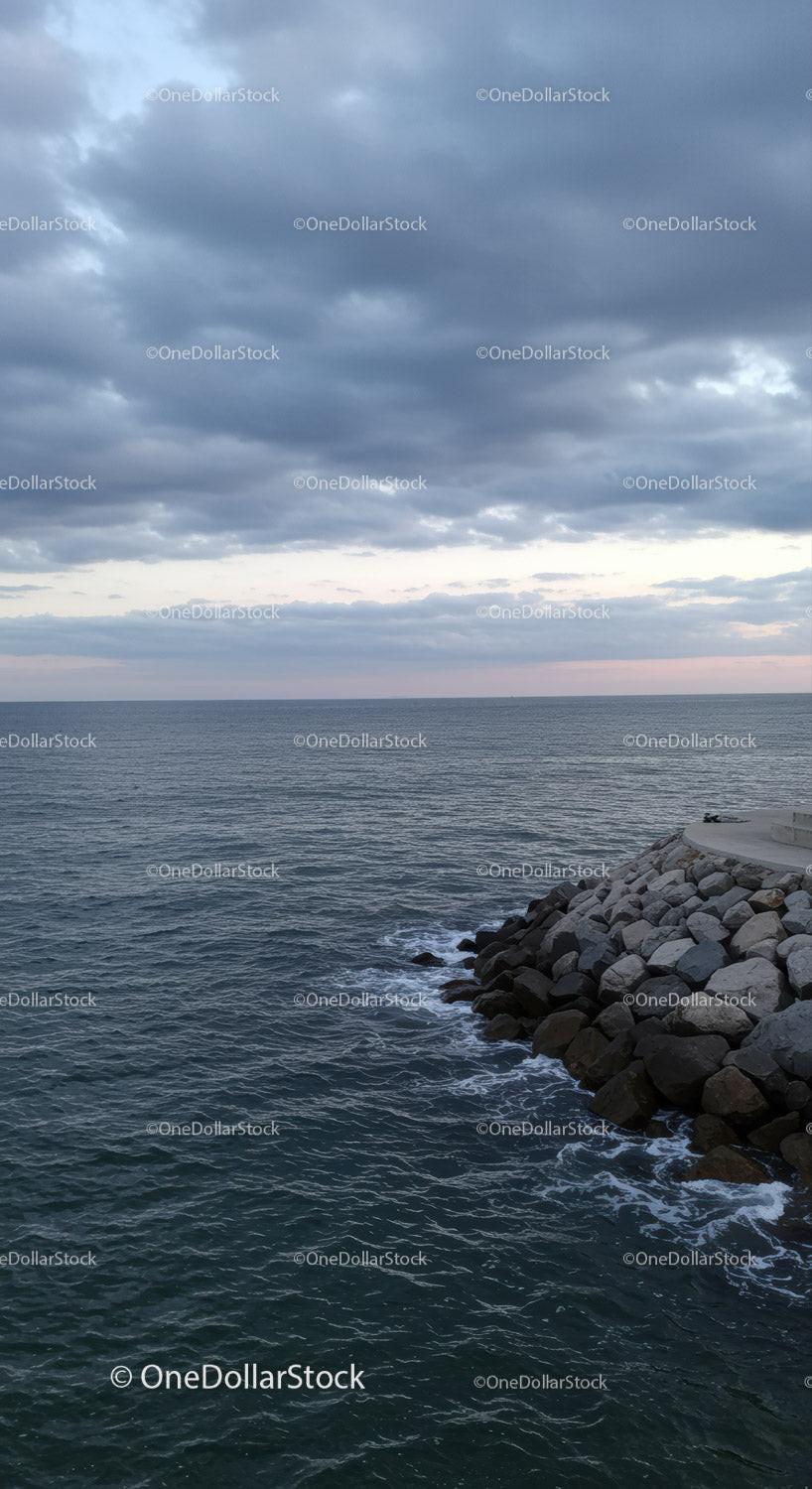 Stormy Sky Over Calm Ocean with Rocky Shore