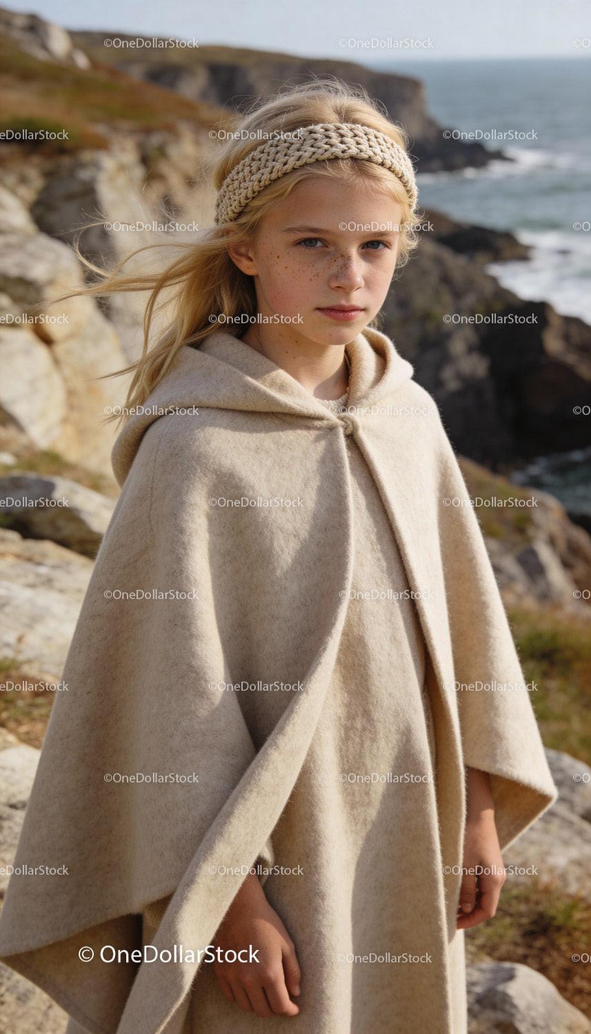 Young girl wearing cozy beige cape by sea cliffs