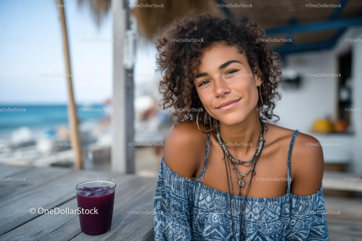 Young Woman with Curly Hair Relaxing at Beachside Cafe with Juice