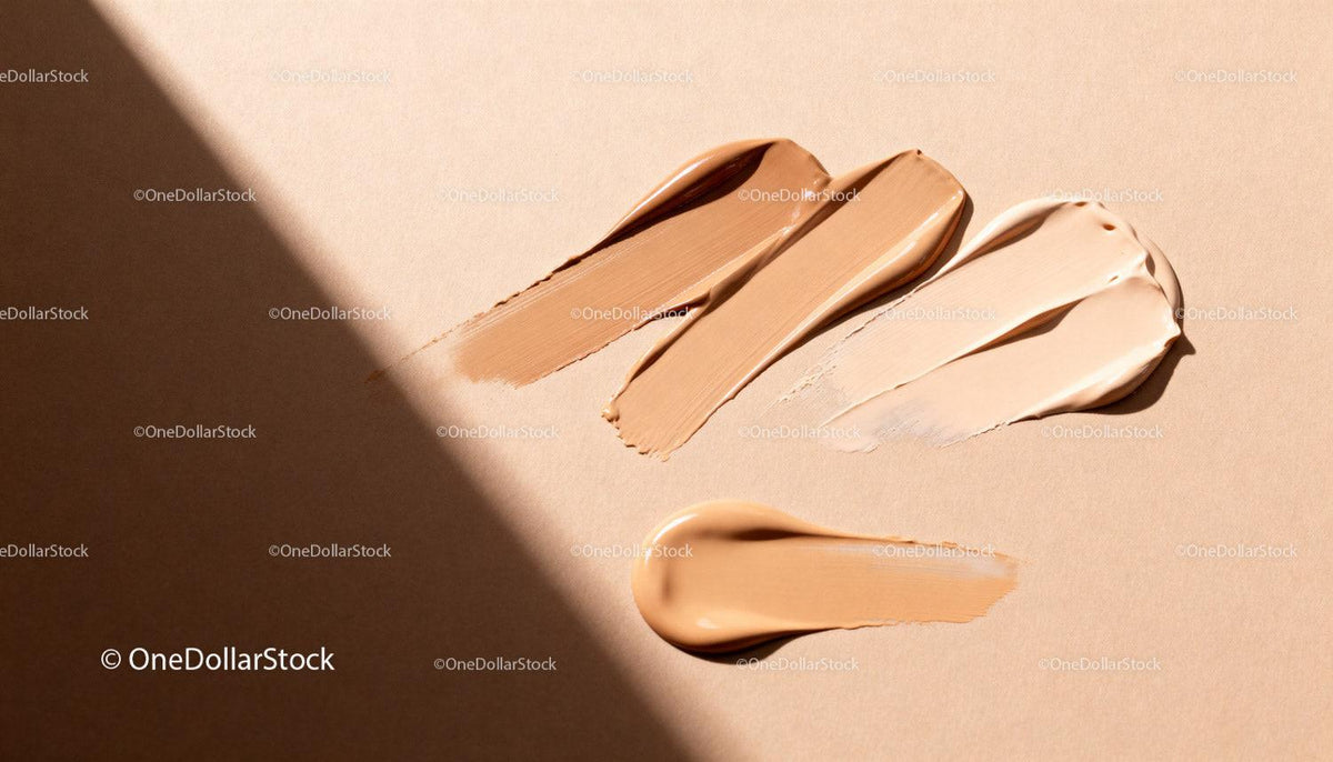 Various shades of liquid foundation makeup on beige surface