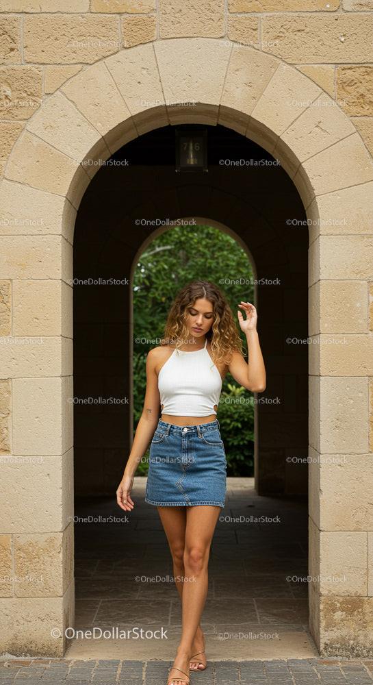 Fashionable Young Woman in Denim Skirt by Stone Archway