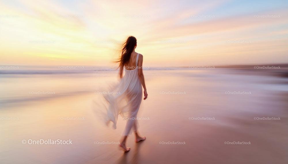 Woman Strolling Along Beach at Sunset with Flowing Dress