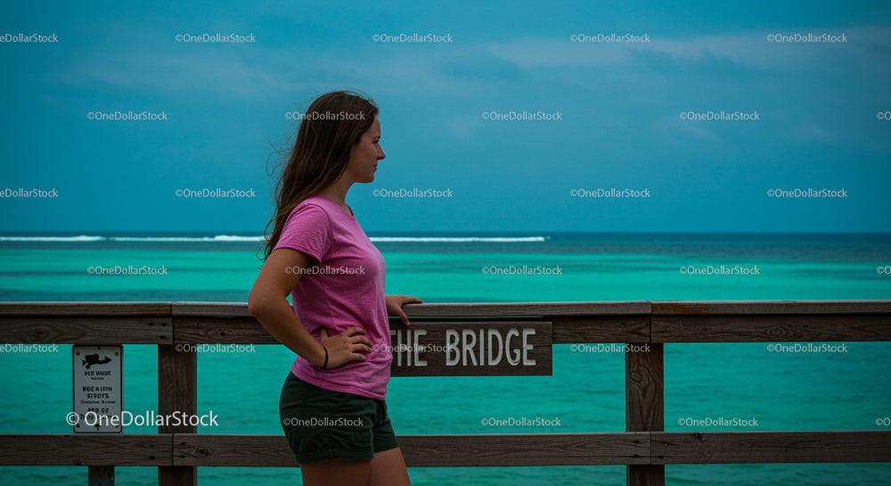 Woman in Pink Shirt on Ocean Bridge