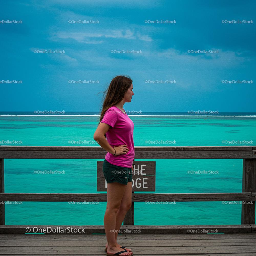 Woman on Wooden Deck Overlooking Turquoise Ocean