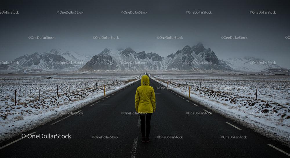 Traveler in Yellow Jacket on Snowy Mountain Road