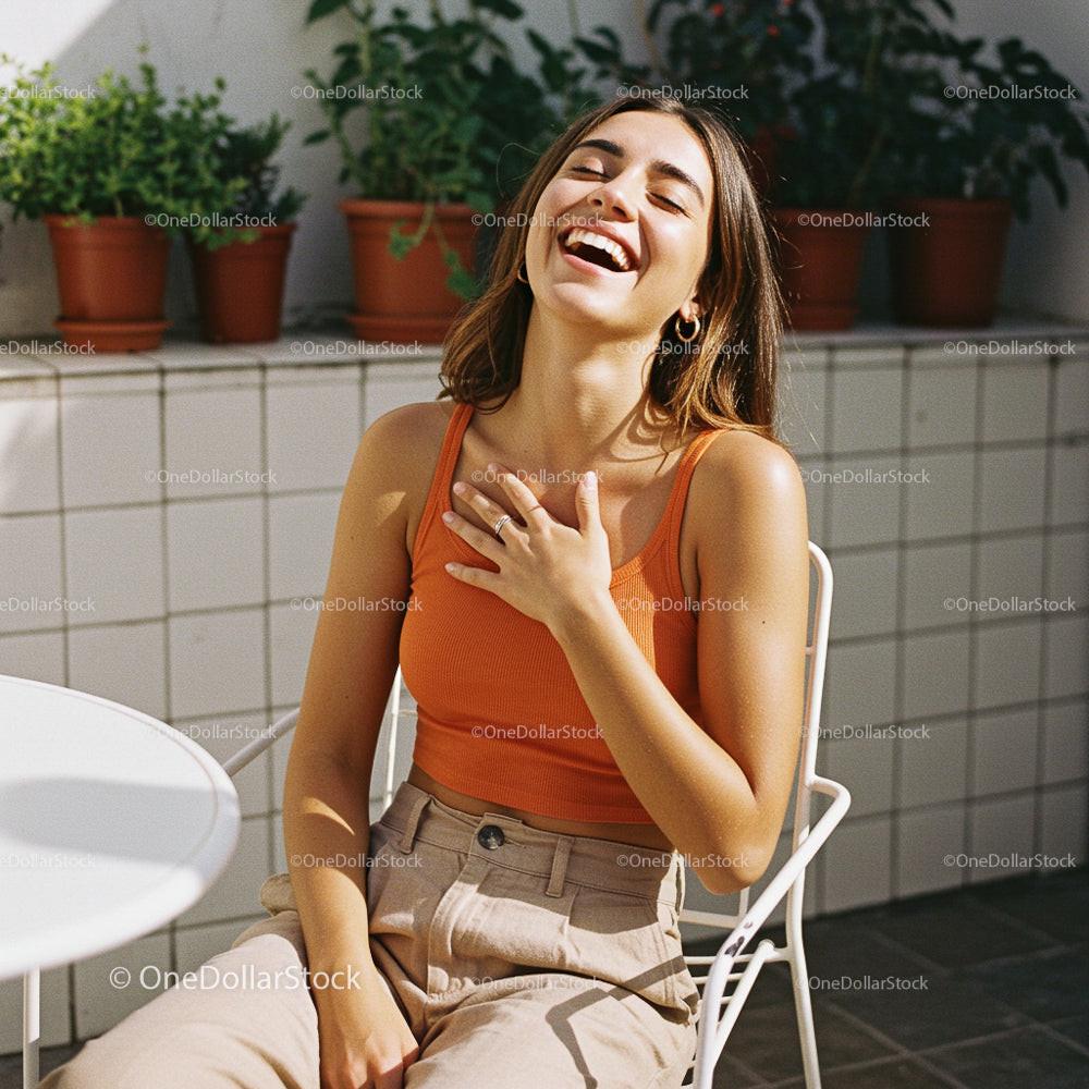 Smiling Woman in Orange Top Sitting Outdoors
