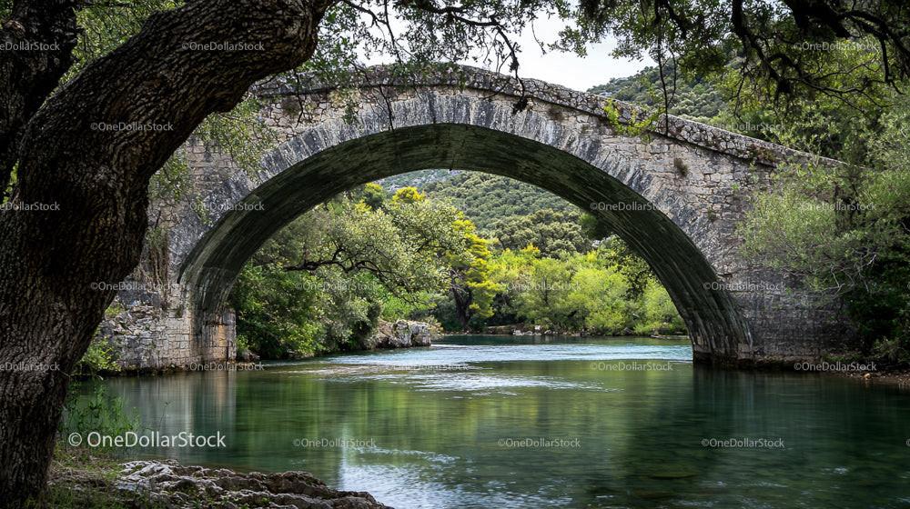 Stone Arch Bridge Over Serene River With Lush Greenery