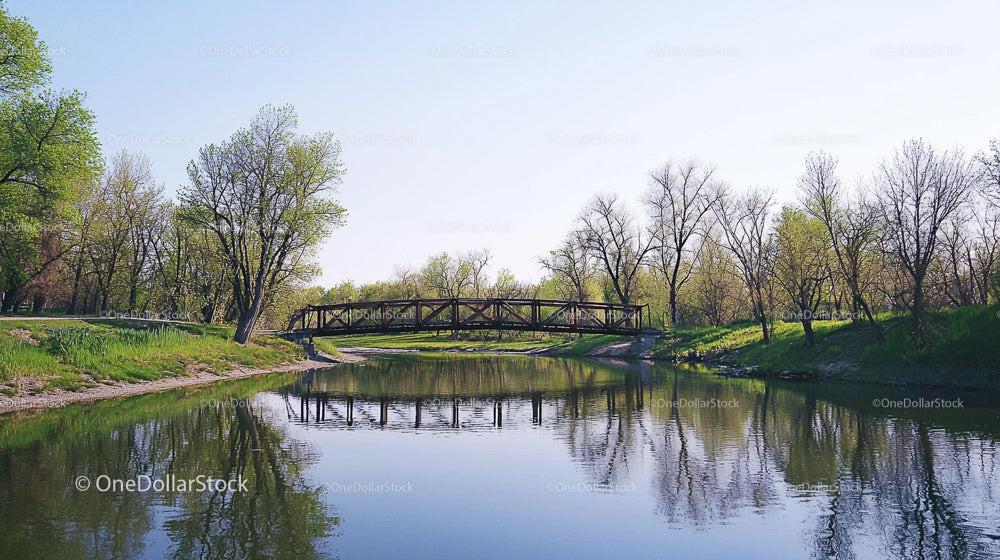 Tranquil River Scene with Reflective Bridge and Spring Foliage