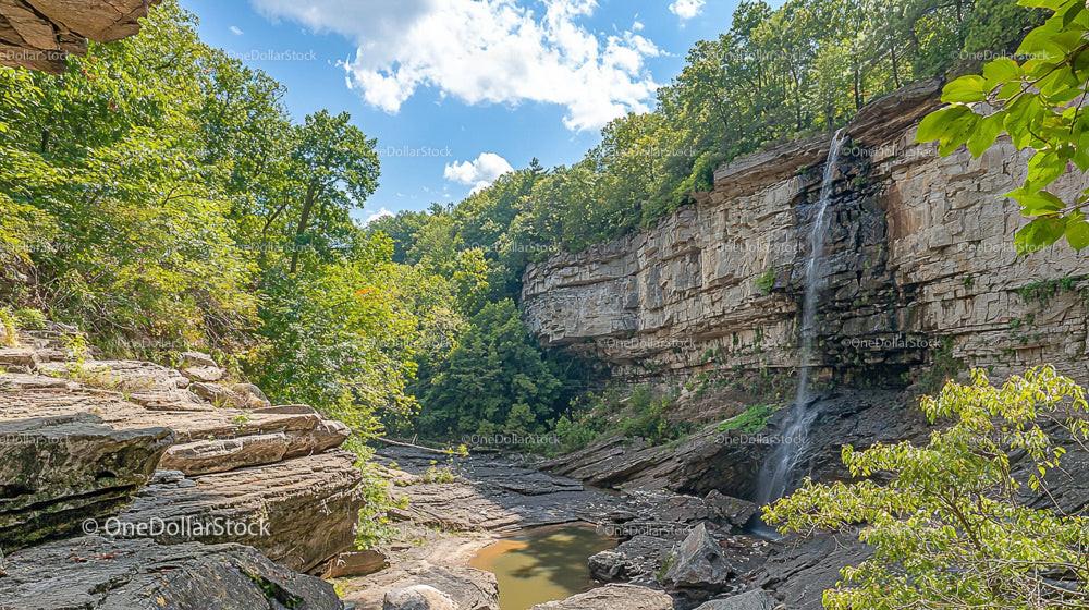 Majestic Waterfall Cascading Over Rocky Cliff Amidst Greenery
