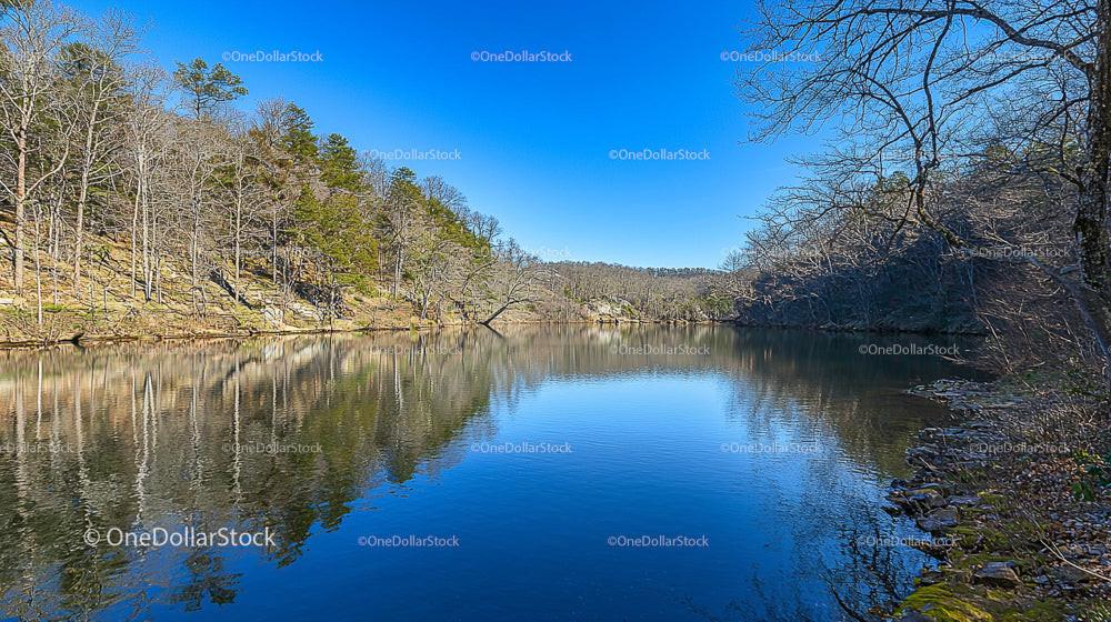 Tranquil Lake Amidst Bare Winter Trees and Clear Sky