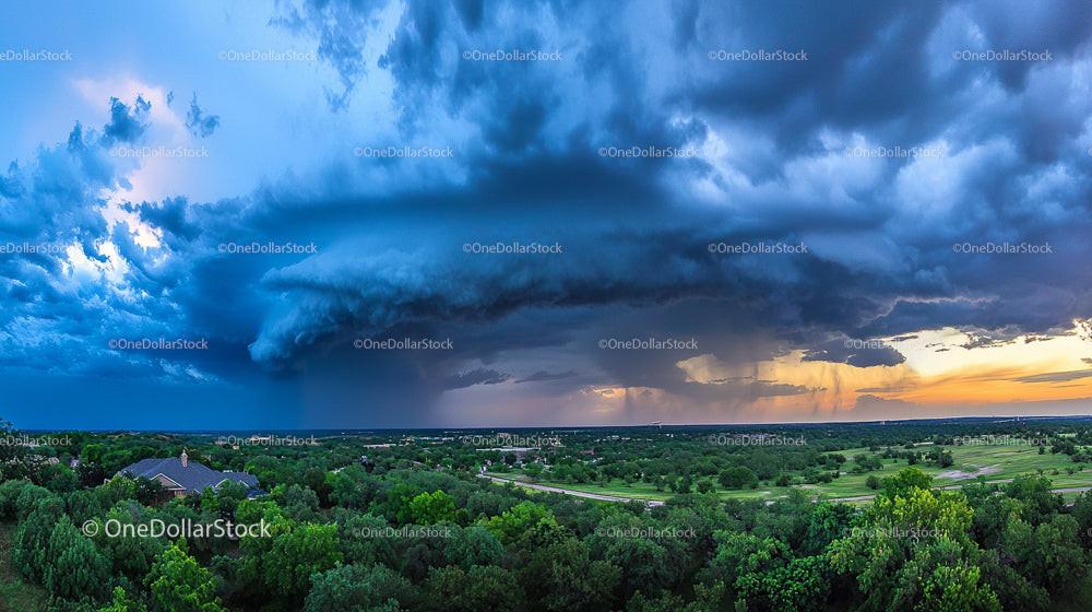 Dramatic Storm Clouds Over Verdant Landscape at Sunset