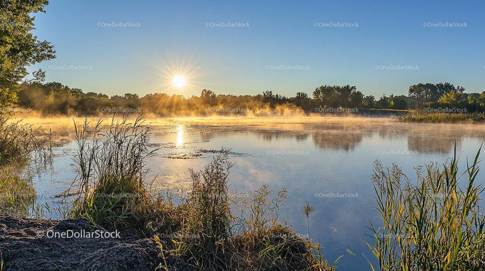 Misty Sunrise Over Calm Lake with Gentle Mist
