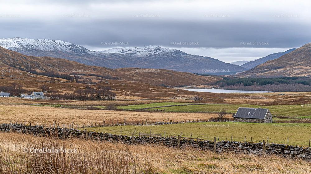 Stone Cottage Amidst Rolling Hills and Snow-Capped Mountains