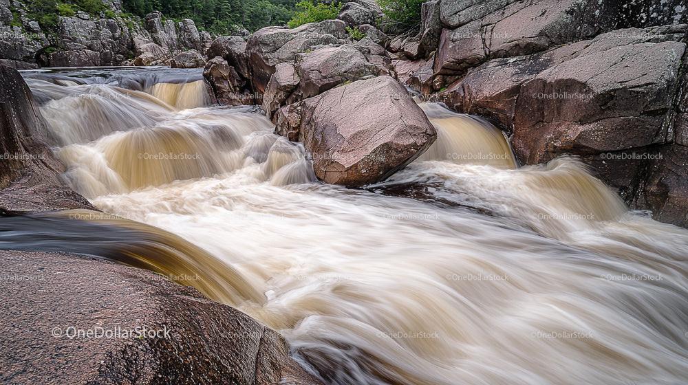 Powerful Waterfall Flowing Over Rugged Rocks in Lush Wilderness
