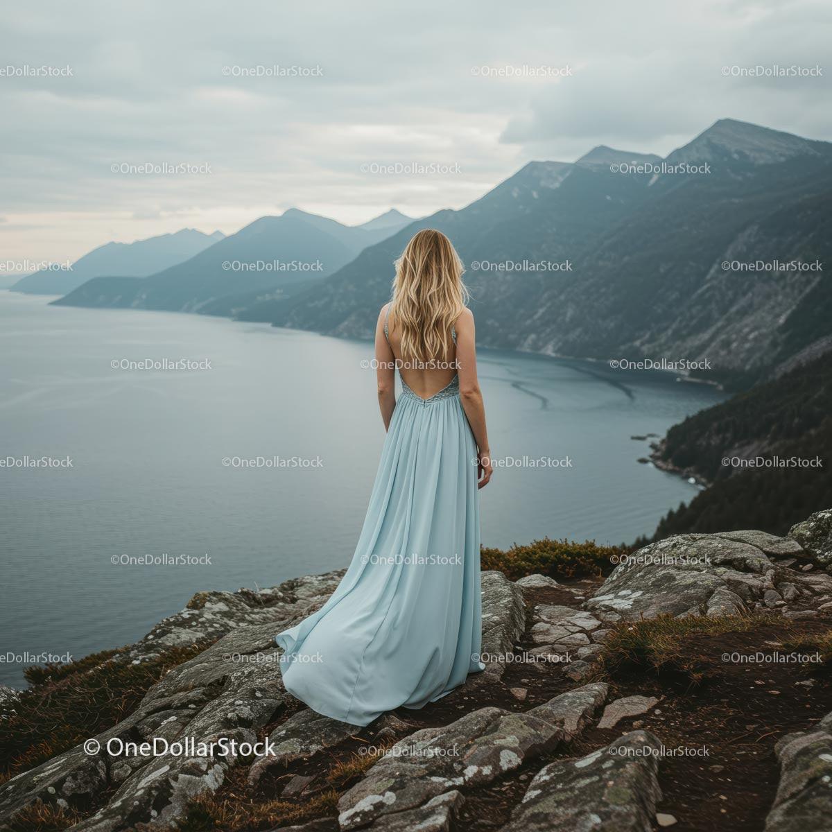 Woman in Elegant Blue Dress Overlooking Majestic Mountains
