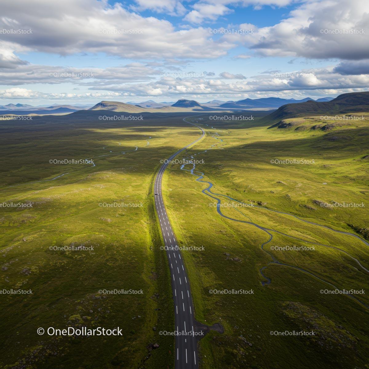Winding Road Through Vast Green Landscape Under Cloudy Sky