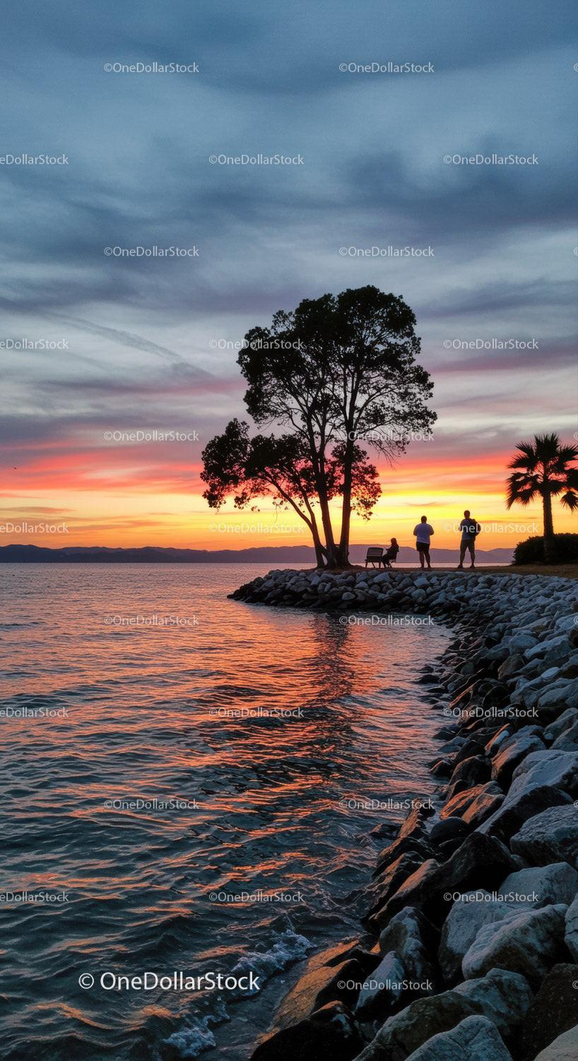 Serene Sunset Over Lake with Silhouetted Trees and People