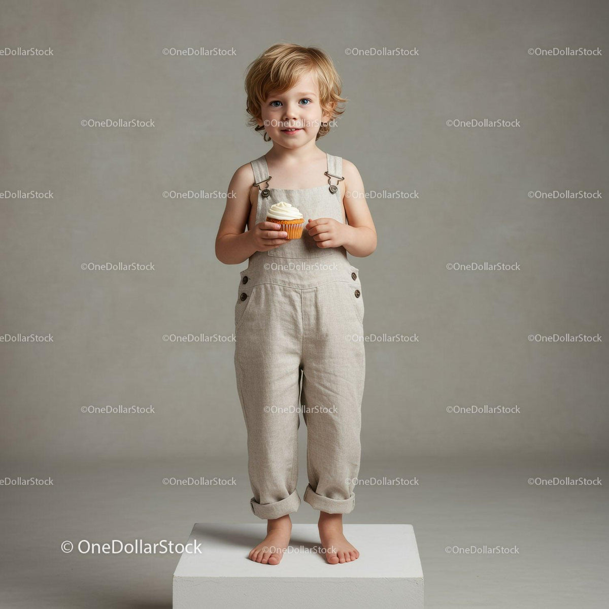 Young blonde child holding cupcake on white platform