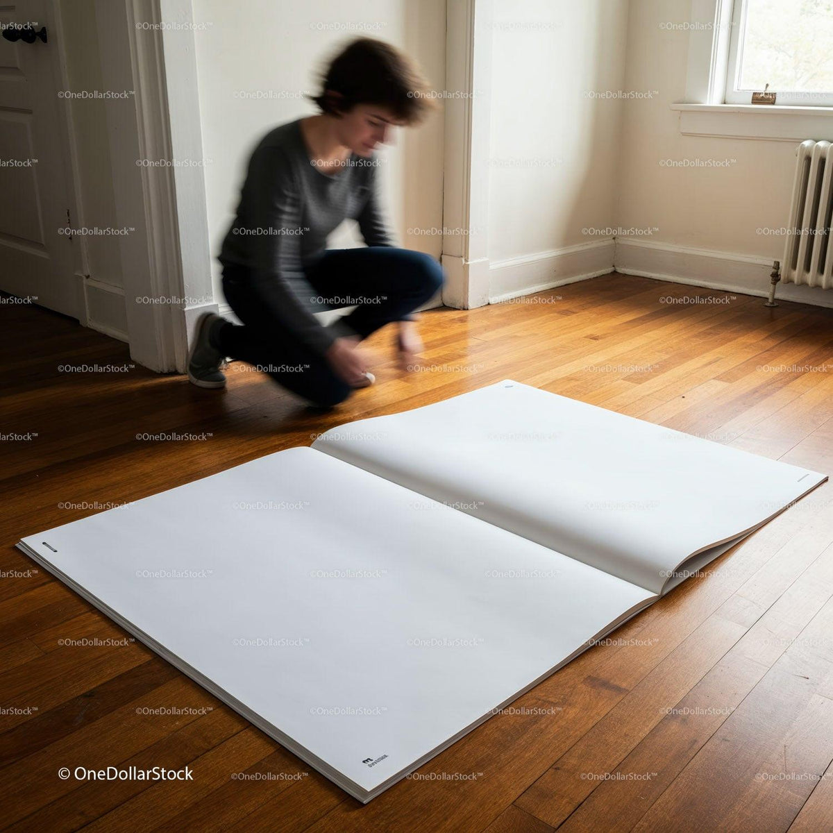 Person kneeling beside giant blank sketchbook on wooden floor JPG Mockup Image preview