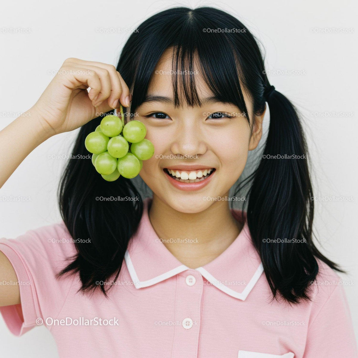 Happy Young Girl Holding Fresh Green Grapes in Casual Pink Polo